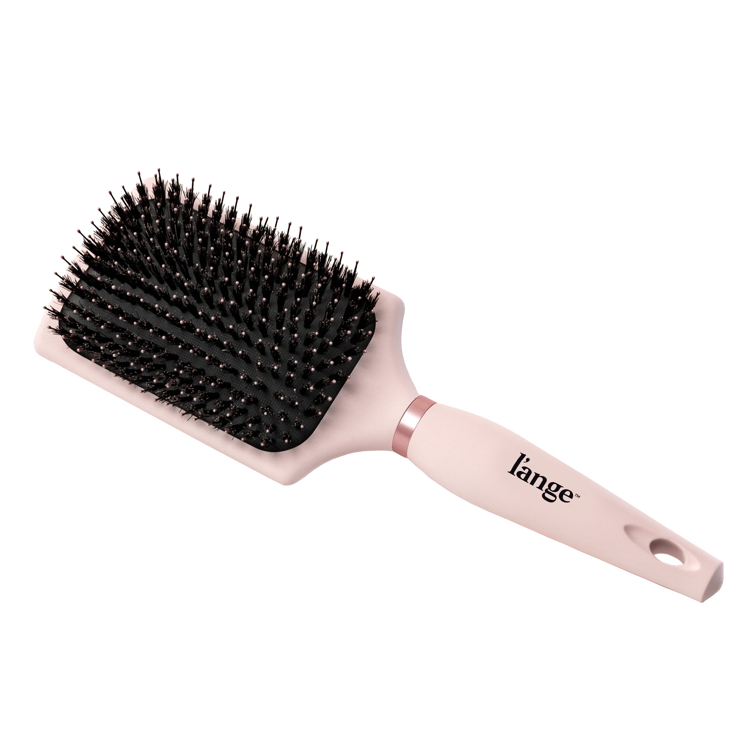 The pink boar bristle brush sits diagonally, showing its handle, the logo, and paddle.