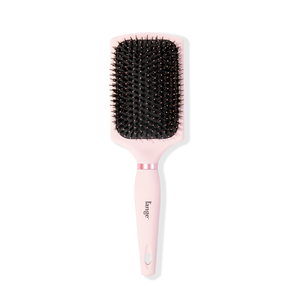 Standing vertically, the pink boar bristle brush displays its rectangular shape & soft-grip handle.