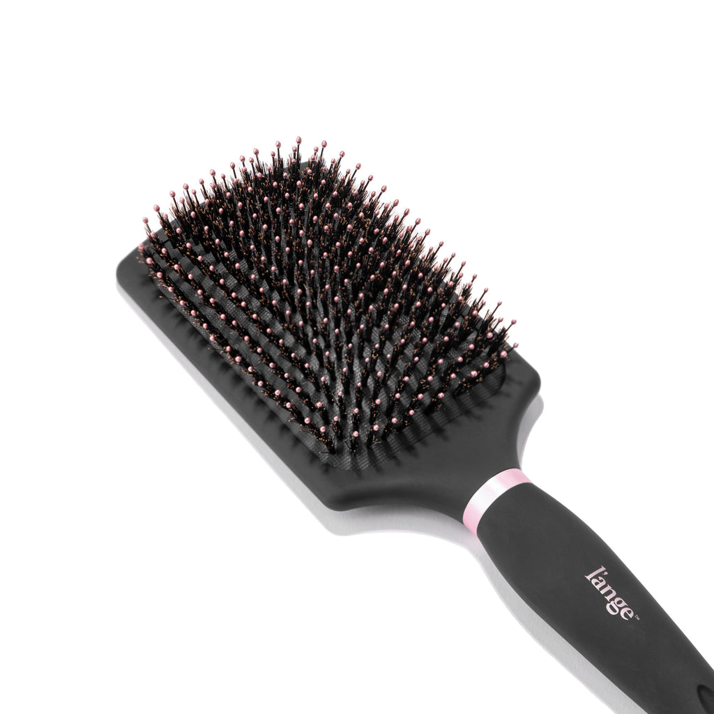 The black Siena Paddle Brush sits diagonally, showing the boar bristles surrounding nylon bristles.