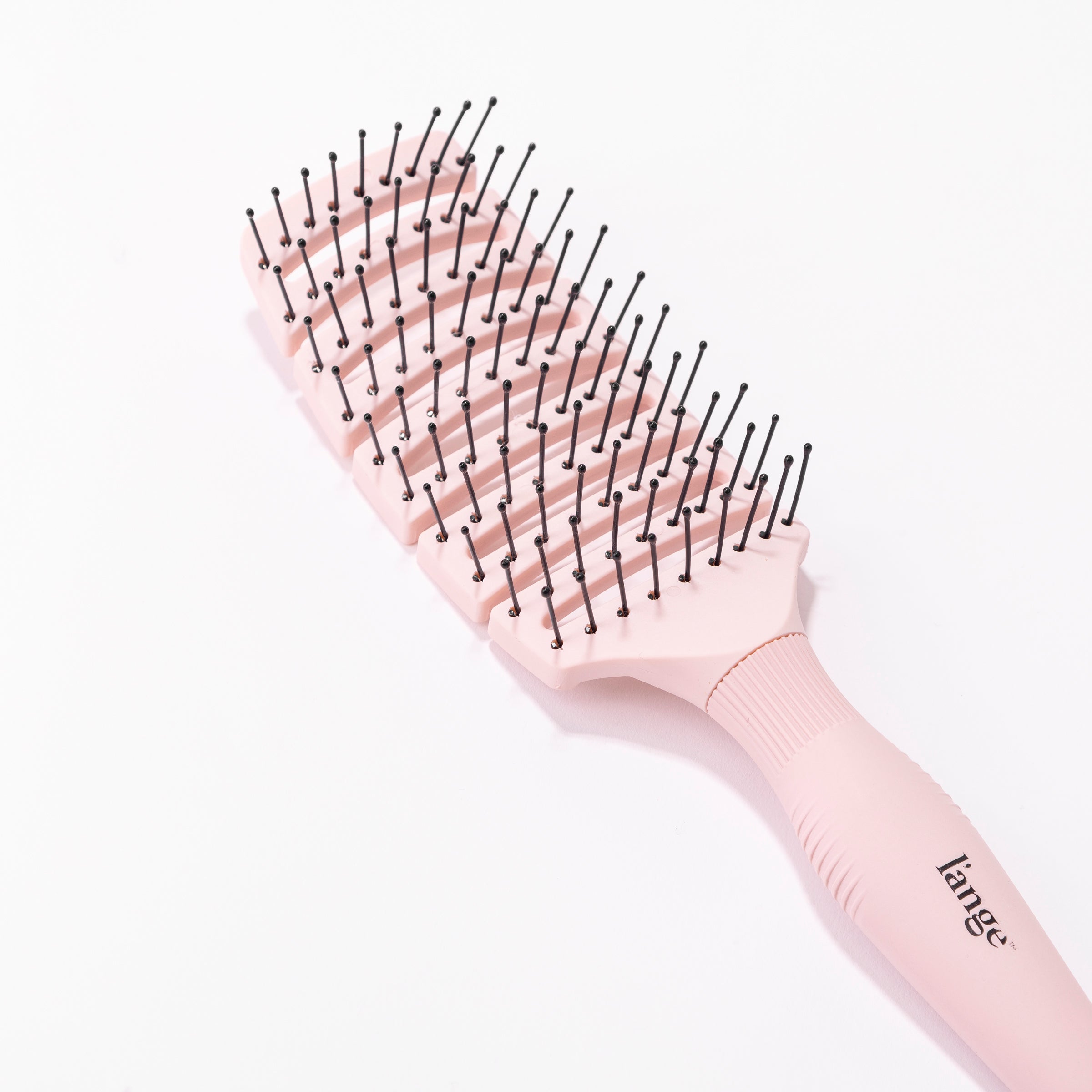 The nylon-tipped bristles & curved, vented paddle of the pink flexible brush are apparent. 
