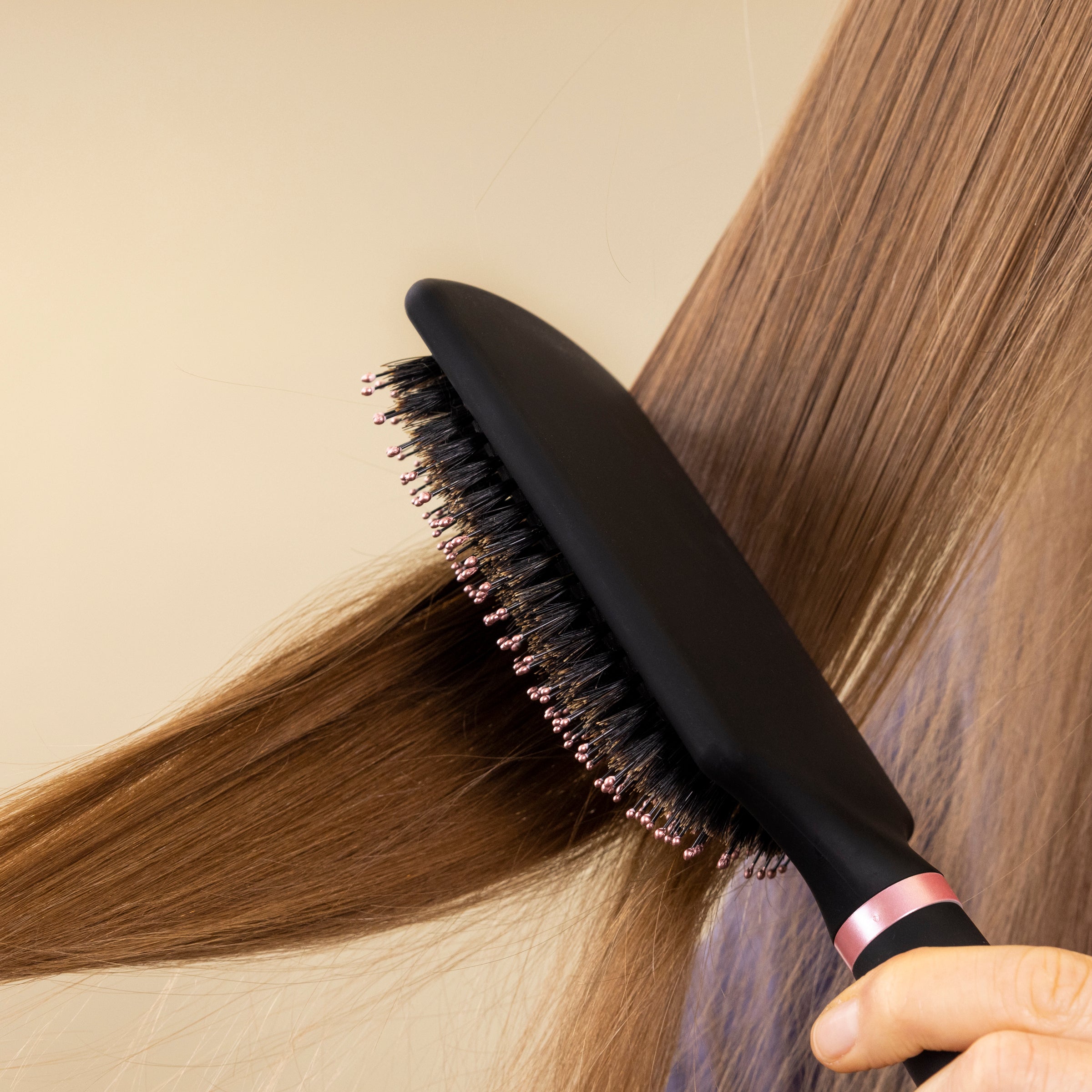 A woman's hair is being brushed by the black boar bristle brush in this close-up.