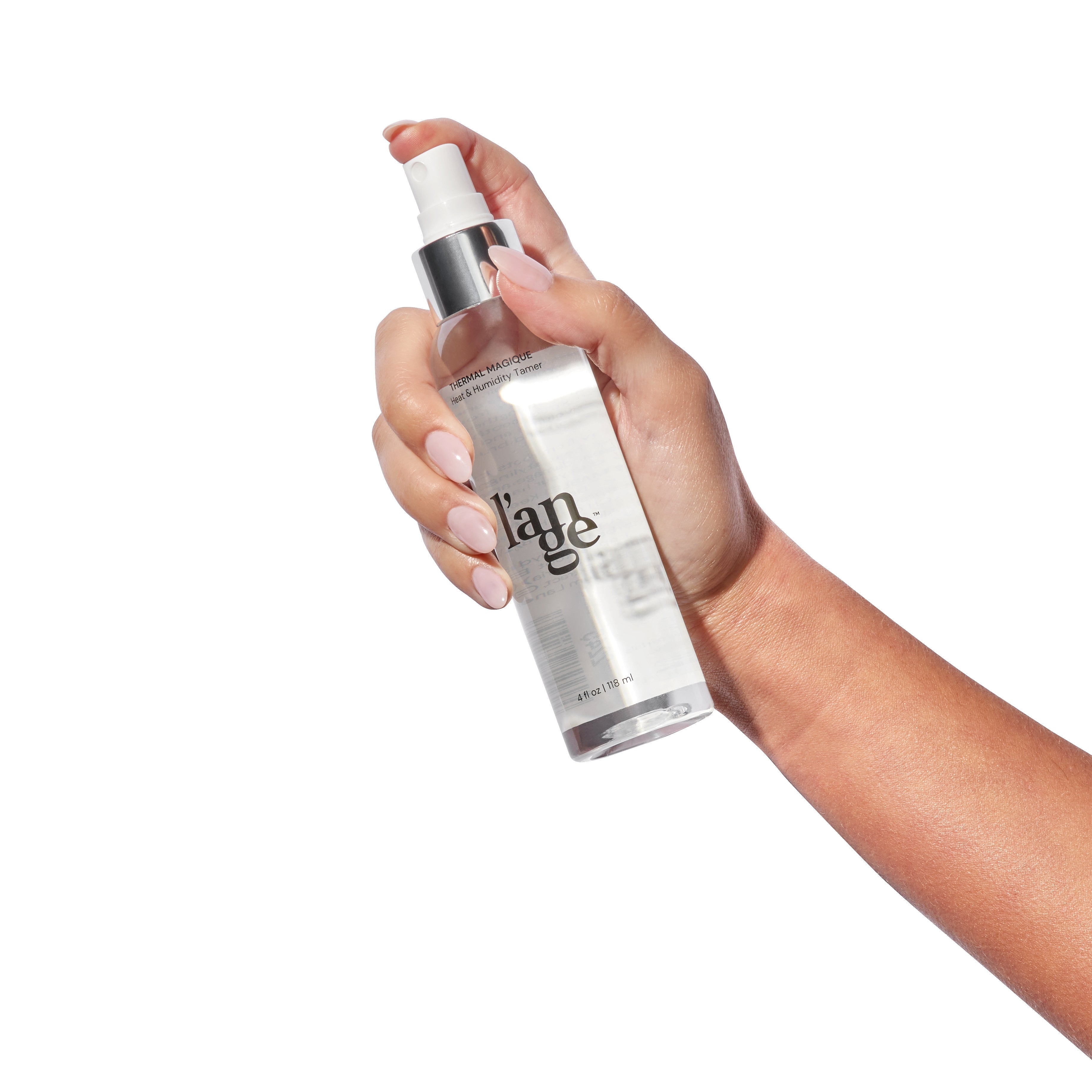 Hand holding a clear bottle of spray with a sleek design, featuring a white label and silver cap.