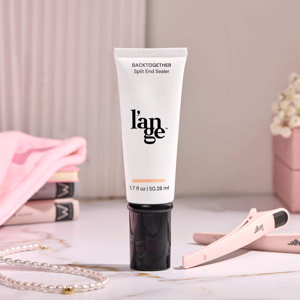 L'ange Back Together Split End Sealer tube, 1.7 fl oz (50.28 ml), on a marble surface with soft pink accents, a hair clip, and a pearl necklace in the background.