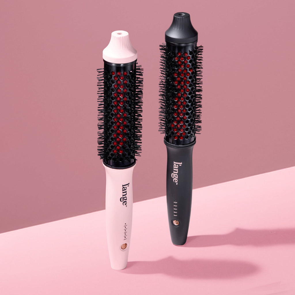 Two L’ange GlamWave heated round brushes in blush pink and matte black on a blush background.