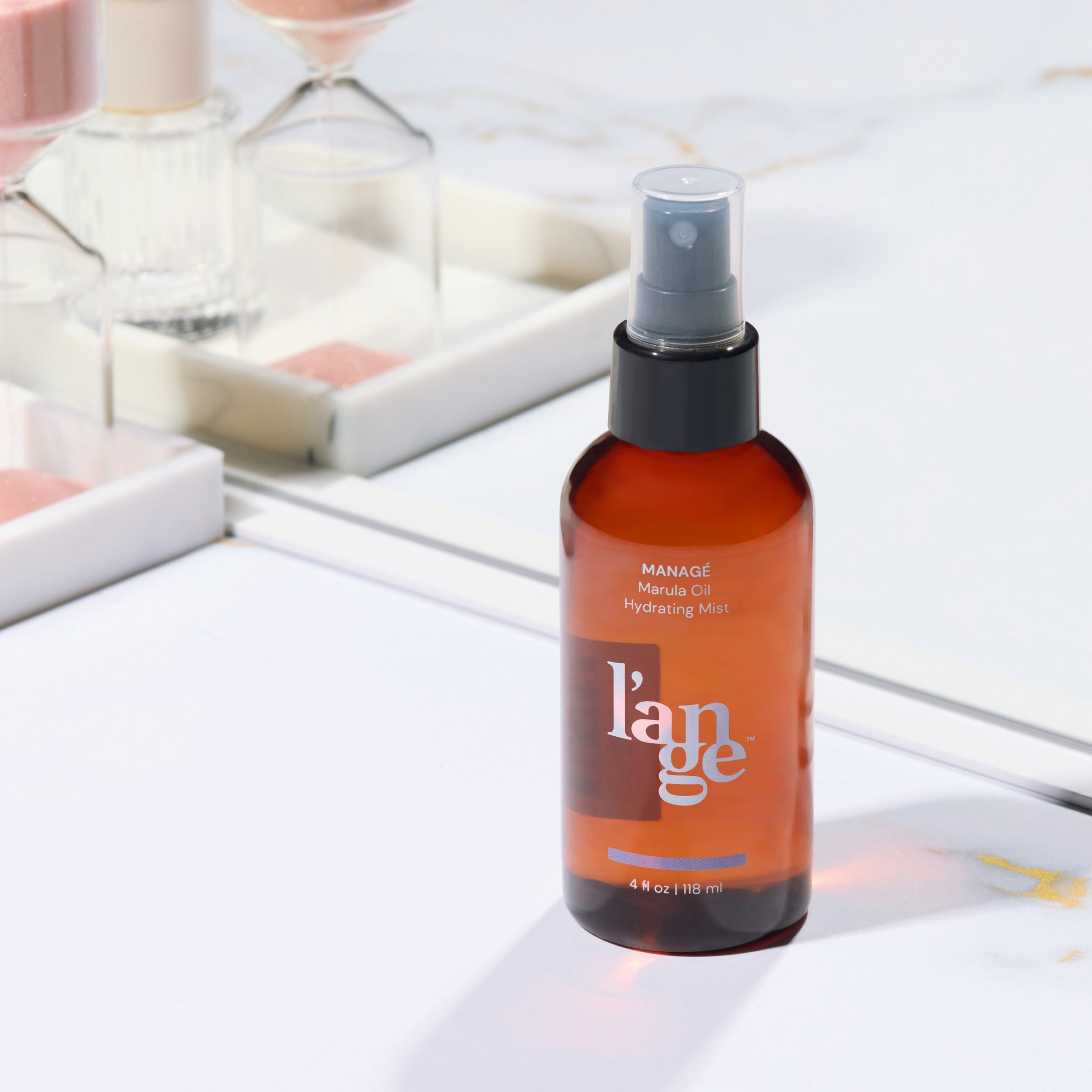L’ange Managé Marula Oil Hydrating Mist on a marble vanity surface with a mirror in the background.