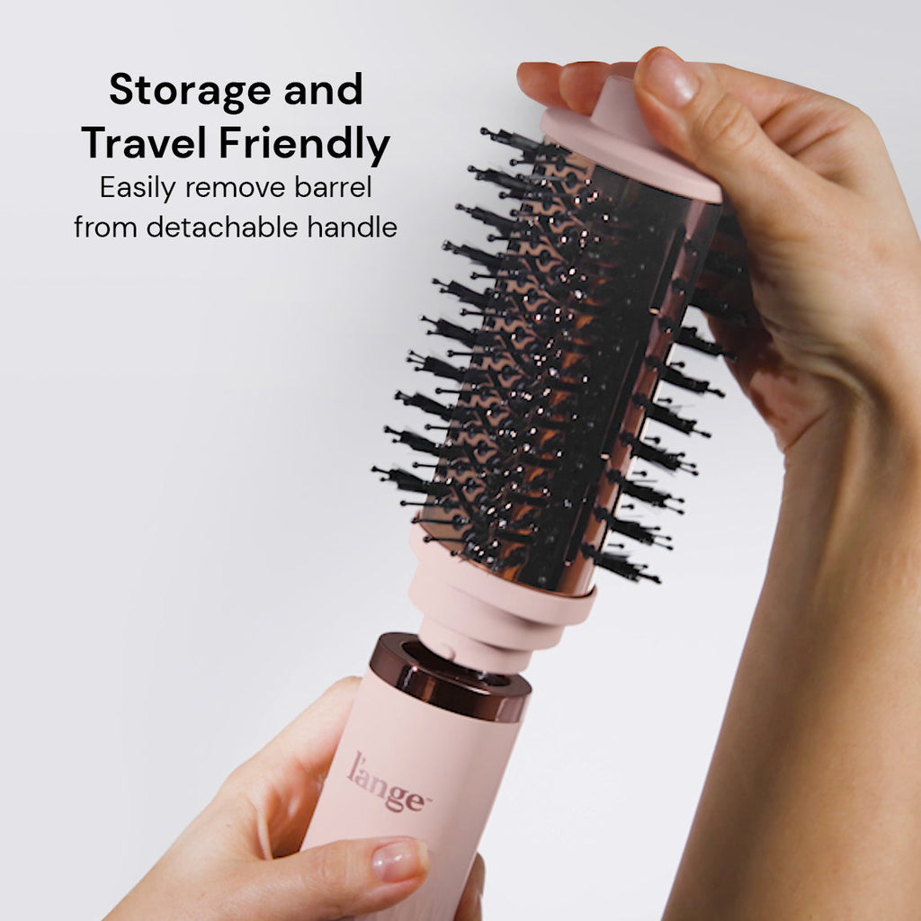 Hands detaching the pink and rose-gold round brush barrel from the L'ange hair dryer handle. Text promotes its storage and travel-friendly design.