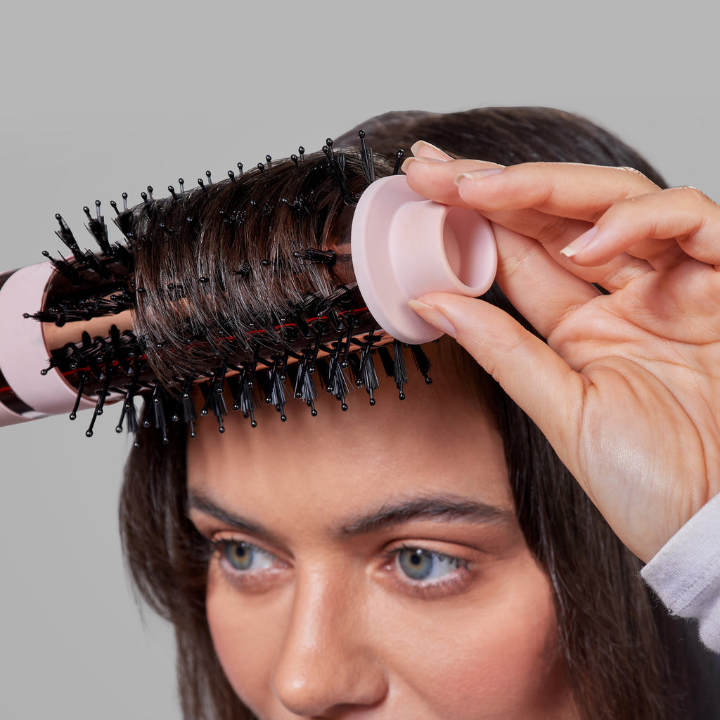 A woman with dark hair and bangs is using the 43mm brush head attachment on Multi-Volume Series to style & define her bangs.