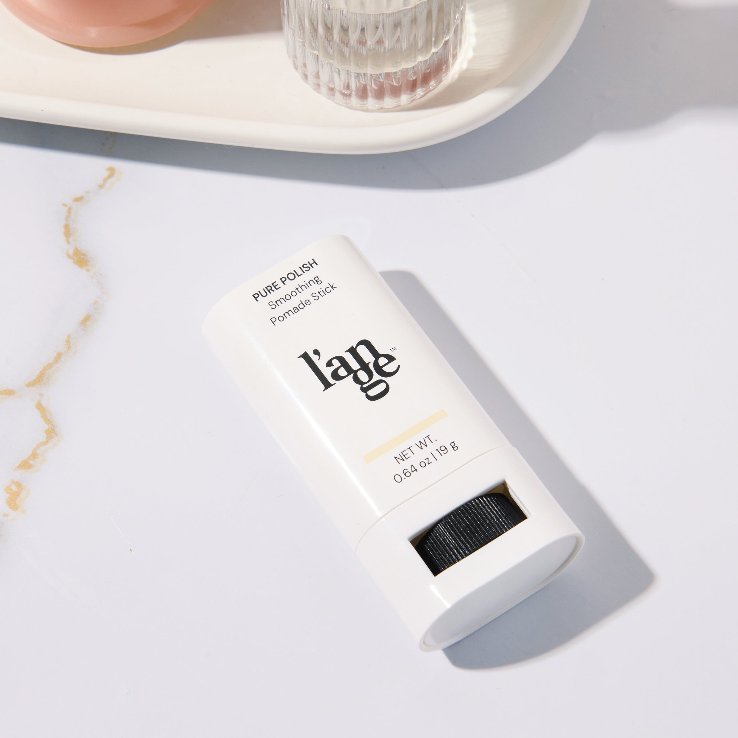 Smoothing Pomade Stick placed on a marble surface 