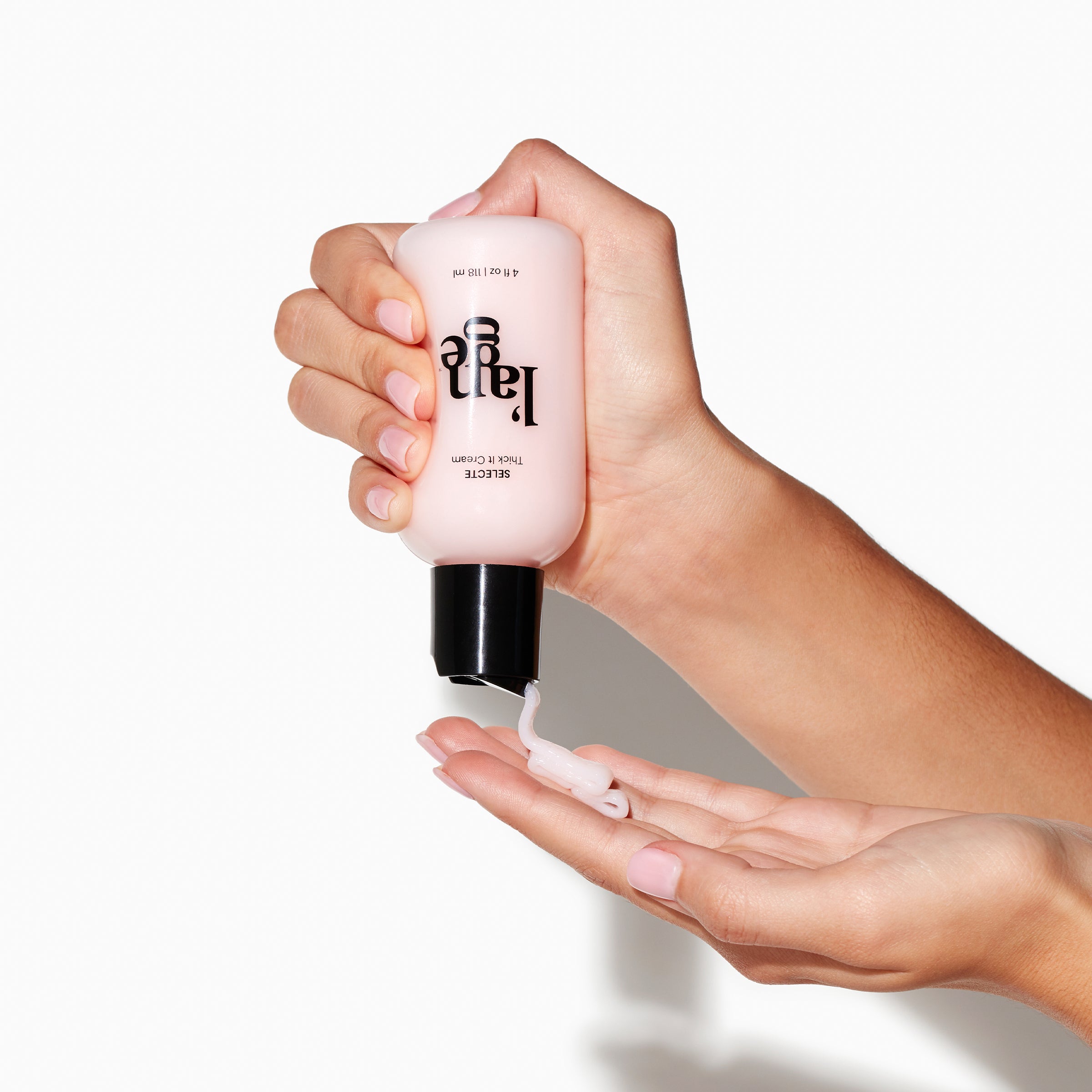 Clear 4fl oz bottle of pink Selecte Thick It Cream held by two light skinned hand with pink cream