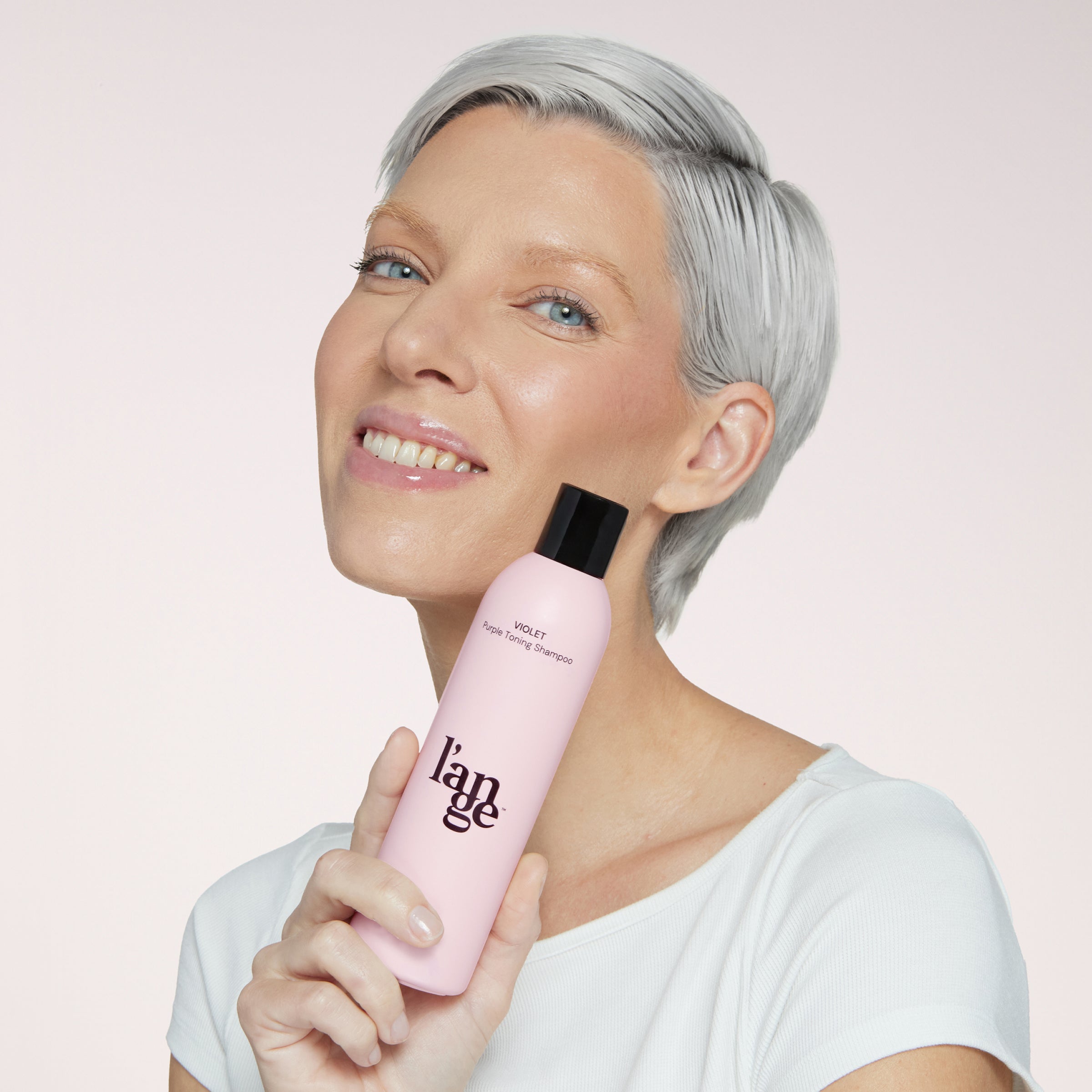 Blonde model holding violet shampoo 